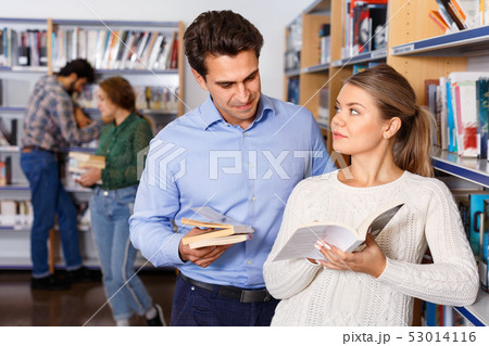 Young handsome man and attractive girl choosing books together in university library 53014116