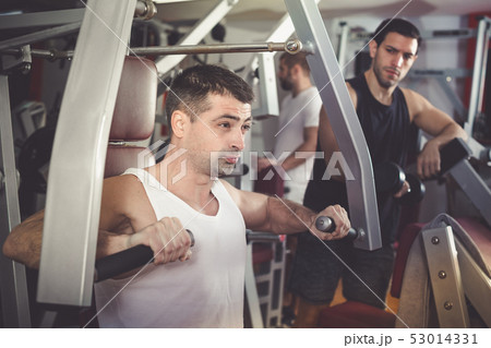 Guy training on fitness machine in gym 53014331