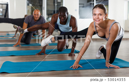 Group of smiling young women and males doing stretching workout 53014355