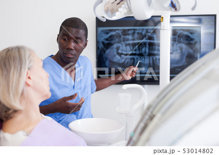 Doctor dentist shows patient an x-ray 53014802