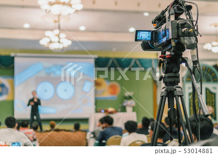 Rear side of Video Cameraman taking photograph to Asian Speaker with casual suit on the stage present the screen in the conference hall or seminar meeting, event and seminar production concept 53014881