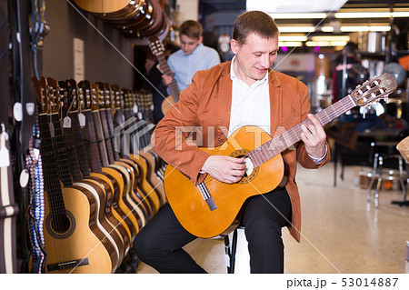 Young male seller showing guitar to boy client 53014887