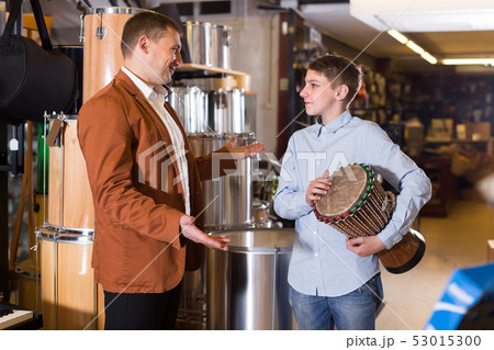 Smiling father and son examining ethnic drums 53015300