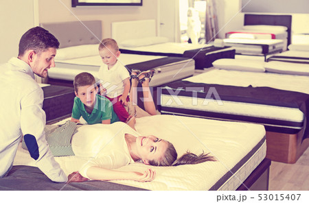 Cheerful woman with her family lying on back on mattress in store Cheerful woman with her family lying on back on mattress in store 53015407