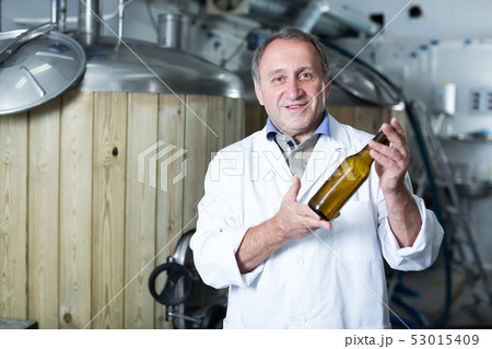 Adult brewer is standing with beer bottle Adult brewer is standing with beer bottle 53015409