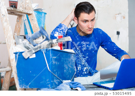 Male contractor working with papers and laptop Male contractor working with papers and laptop 53015495