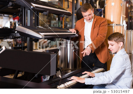 Happy boy and father deciding on synthesizer 53015497