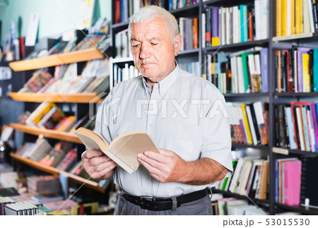 Old male is choosing book for reading in free time in bookstore. 53015530