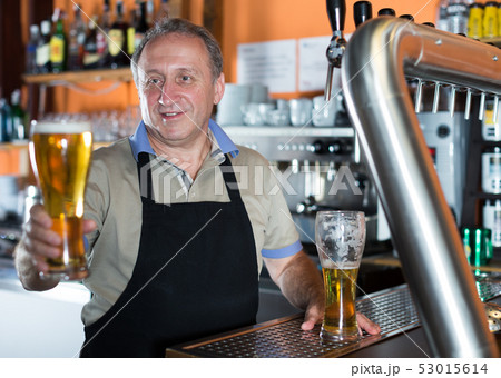 Barman is standing with golden beer 53015614