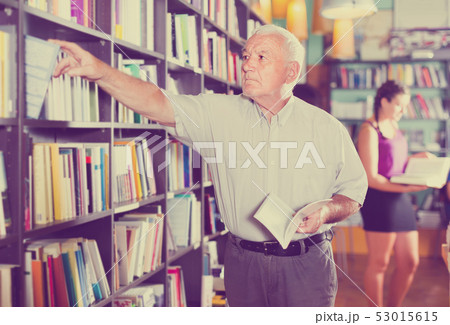 Old male is choosing book for reading in free time in bookstore. Old male is choosing book for reading in free time in bookstore. 53015615