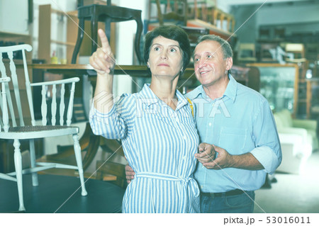 Man with wife are choosing old antique chair in shop 53016011