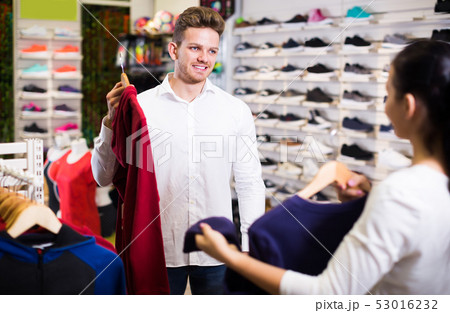 Smiling loving couple deciding on new sportswear Smiling loving couple deciding on new sportswear 53016232