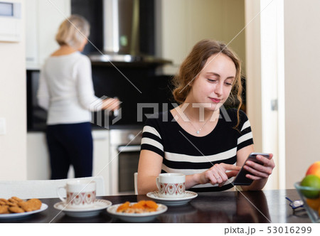 Woman with phone at kitchen Woman with phone at kitchen 53016299
