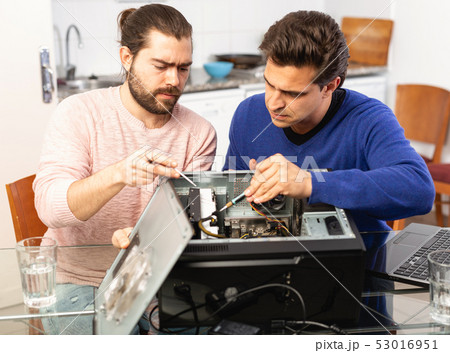 Two men repairing a desktop computer Two men repairing a desktop computer 53016951
