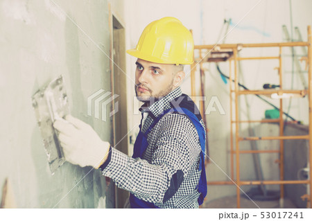 Workman in the helmet is plastering the wall Workman in the helmet is plastering the wall 53017241