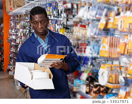 salesman arranging different goods on stand in shop 53017971