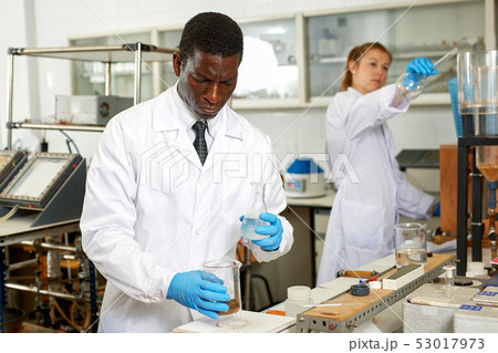 Serious male scientists with glass test tubes during chemical experiment 53017973