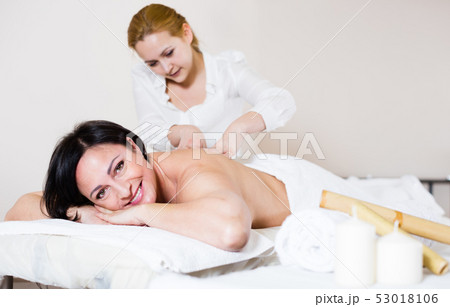 Positive woman likes work of young masseur 53018106