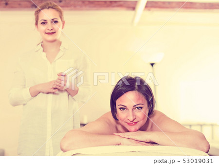 Young female massagist with smiling client before massage procedure Young female massagist with smiling client before massage procedure 53019031