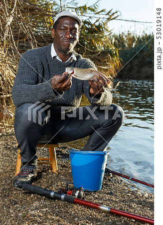 Fisherman holding fish in his hands 53019148