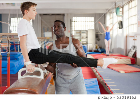 Fine African male coach helping teenage boy 53019162