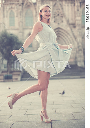 smiling woman holding dress in the hand 53019168