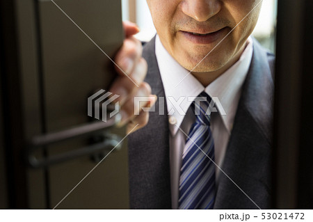 玄関を開けて薄笑いを浮かべる無精髭のビジネスマン　（訪問販売　営業マン） 53021472