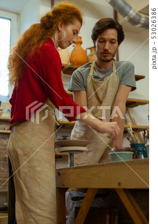 Curious lady with wild hairstyle learning pottery mastery 53026386