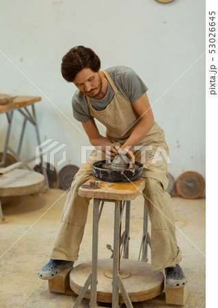 Dark-haired man with beard manufacturing new clay pots Dark-haired man with beard manufacturing new clay pots 53026645