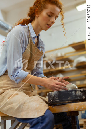 Focused young lady enjoying time spending in pottery workshop Focused young lady enjoying time spending in pottery workshop 53026717