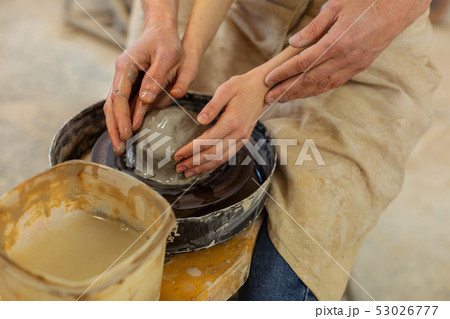 Girl with tiny hands molding wet clay on a wheel 53026777