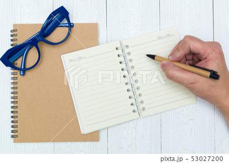 Man hand writing on blank page of notebook paper 53027200
