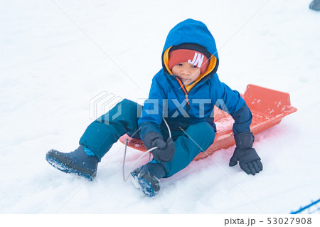 Little Japanese boy is sliding down the snow sled 53027908