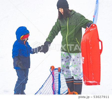 Mother is helping her boy to ride the sled Mother is helping her boy to ride the sled 53027911