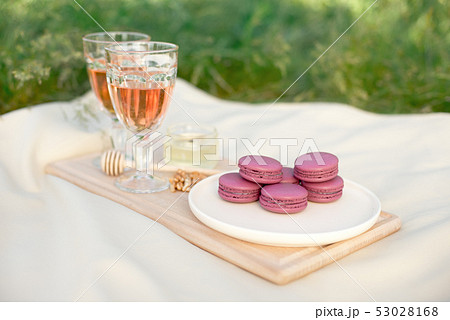 Light pink and fuchsia pink french macaroons or macaroons with glass goblets of pink wine in a round 53028168