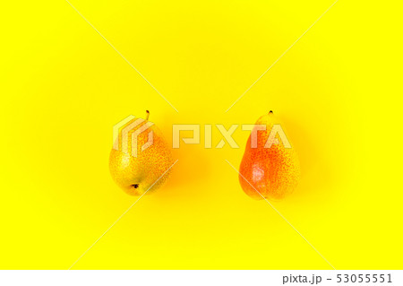 Two appetizing ripe pears with red side on a yellow background. Two appetizing ripe pears with red side on a yellow background. 53055551