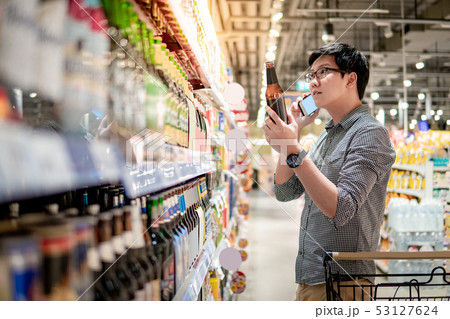 Asian man shopping beer using phone Asian man shopping beer using phone 53127624