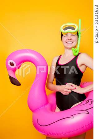 Photo of woman with scuba and in swimsuit with life preserver on empty orange background Photo of woman with scuba and in swimsuit with life preserver on empty orange background 53131623