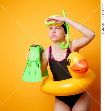 Photo of woman with flippers in hands, swimming mask and with life preserver on empty orange Photo of woman with flippers in hands, swimming mask and with life preserver on empty orange 53131627