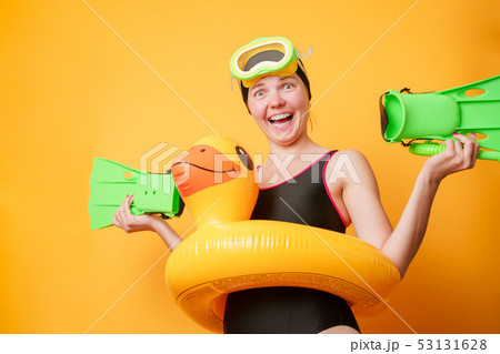 Photo of cheerful woman with flippers in hands, swimming mask and with life preserver on empty Photo of cheerful woman with flippers in hands, swimming mask and with life preserver on empty 53131628
