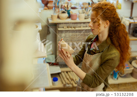 Satisfied long-haired pottery master observing her first creations 53132208