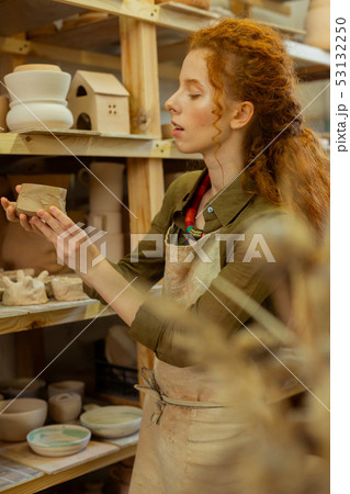 Attentive ginger girl enjoying different clay figures and pots Attentive ginger girl enjoying different clay figures and pots 53132250