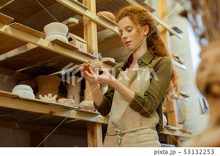 Interested good-looking long-haired woman in green shirt holding tiny creation Interested good-looking long-haired woman in green shirt holding tiny creation 53132253