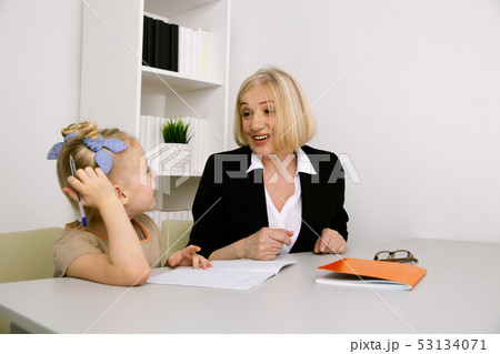 Girl with grandmother sitting on the desk and learning. Girl with grandmother sitting on the desk and learning. 53134071