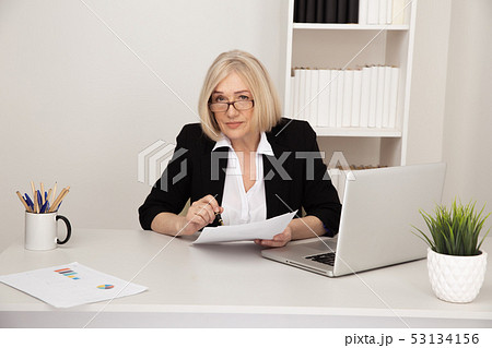 Business lady in office holding paper documents and smiling. 53134156