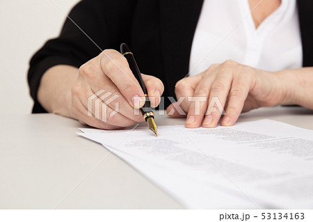Female office worker writing on paper documents by pen. Female office worker writing on paper documents by pen. 53134163