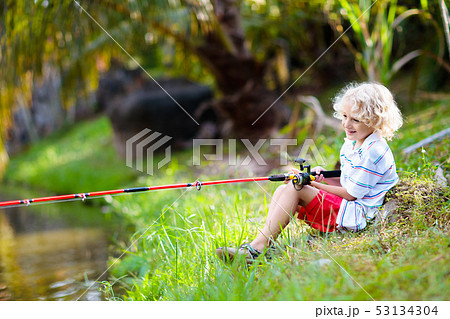 Boy fishing. Child with red rod catching fish in river on sunny