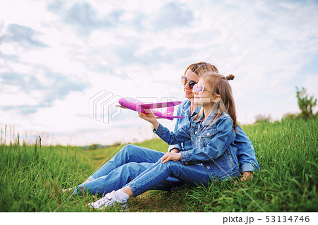 Girl playing with plane near mother Girl playing with plane near mother 53134746