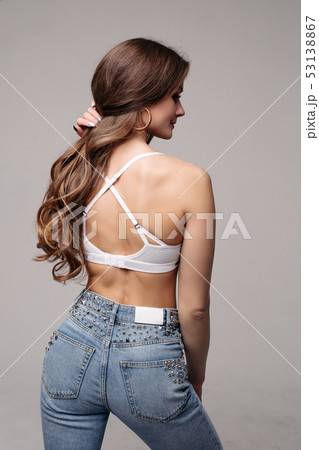 Brunette slim model in jeans and sports bra. - Stock Photo