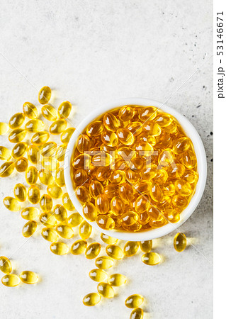 Fish oil capsules (omega 3) in white bowl on gray Fish oil capsules (omega 3) in white bowl on gray 53146671